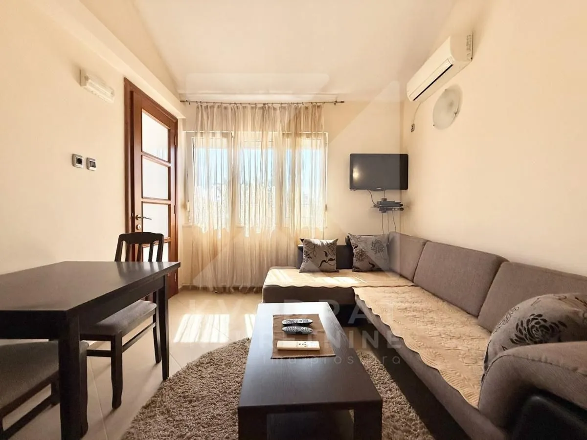 Living room with a sofa, dining table, and a window with curtains.