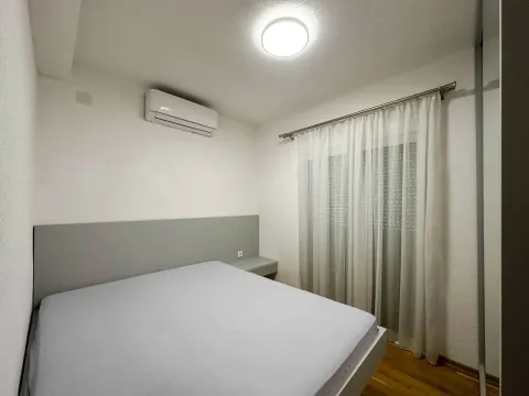 Furnished bedroom with a double bed, air conditioning, and a window with curtains. - image 2