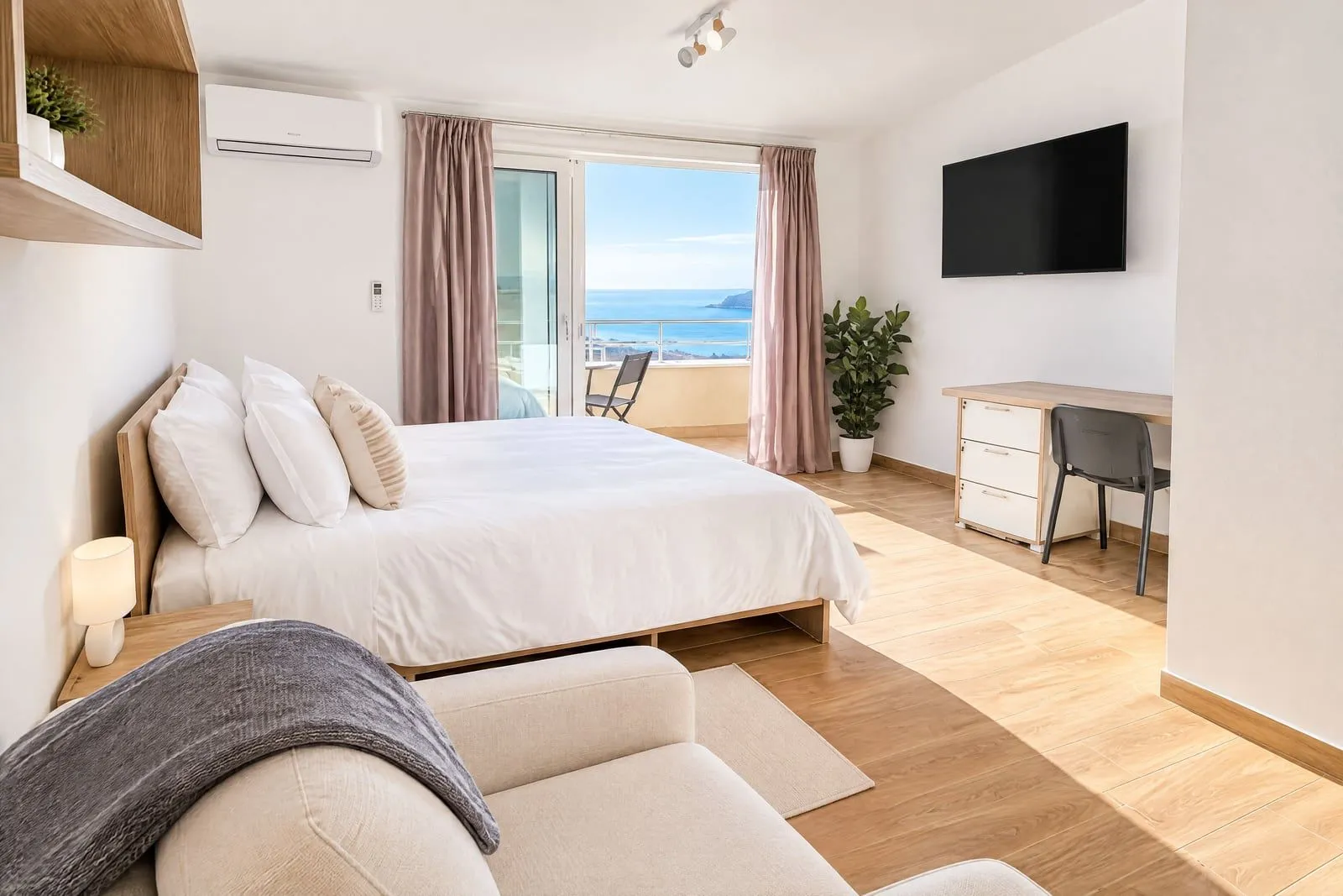 Spacious bedroom with a double bed, desk, and access to a terrace with a sea view.