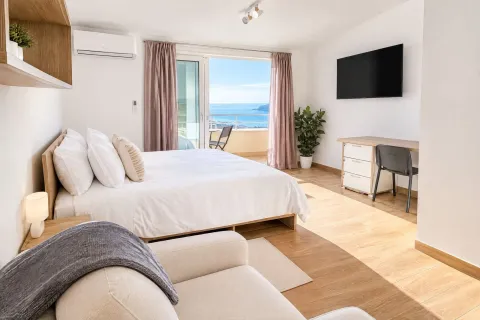 Spacious bedroom with a double bed, desk, and access to a terrace with a sea view. - image 8