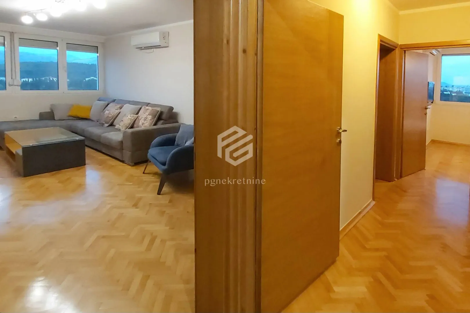 View from the hallway into the living room with a sofa and parquet flooring.