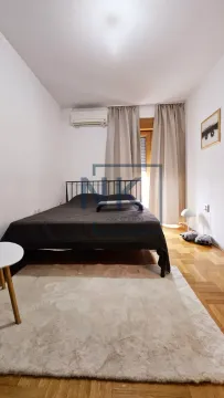 Namještena spavaća soba sa bračnim krevetom, klima uređajem i prozorom sa zavjesama. - image 4