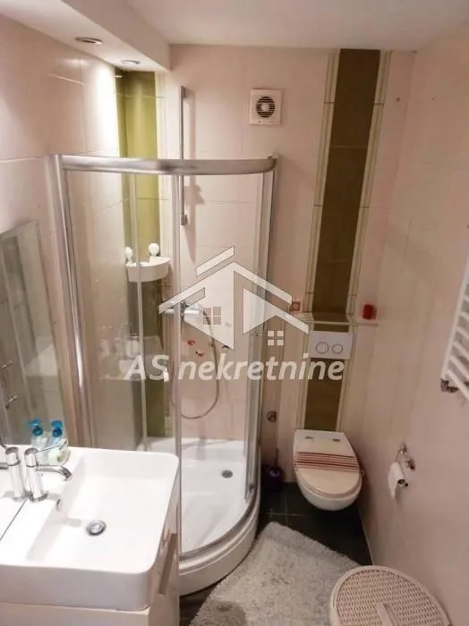 Compact bathroom with a shower cabin, washbasin, and toilet.