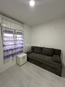 Small living room with a dark sofa, a white cabinet, and a window with curtains. - image 5