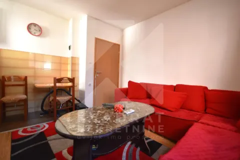 Living room with a red sectional sofa, coffee table, and a dining table with chairs. - image 3