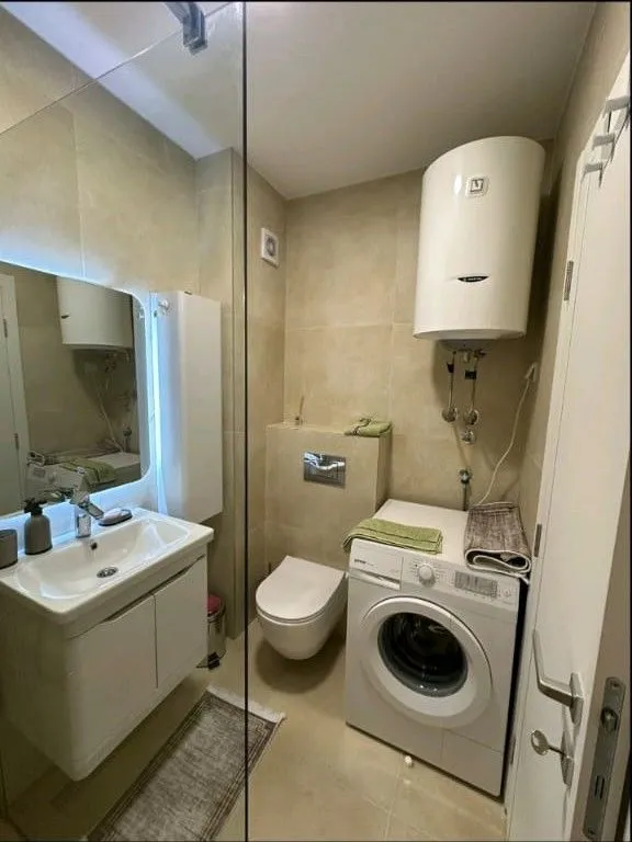 Bathroom equipped with sanitary ware, a shower cabin, a water heater, and a washing machine.