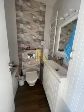 Small bathroom with a shower, washbasin, and toilet. - image 17