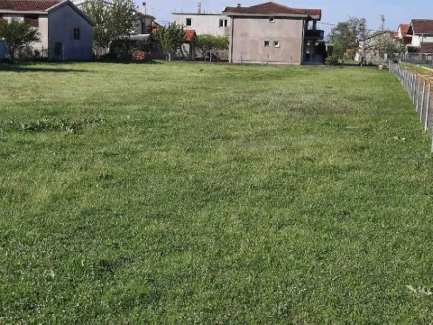 Ravan travnati plac u naselju sa okolnim kućama. - image 3