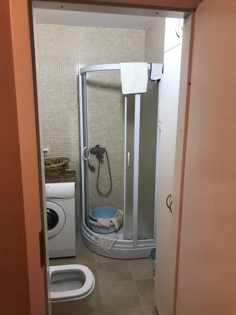Jednostavno kupatilo sa tuš kabinom i veš mašinom.