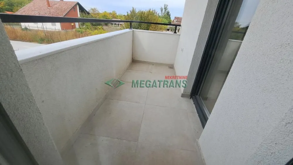 Prazan balkon sa keramičkim pločicama i metalnom ogradom.