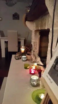 A fireplace in the living room decorated with candles, with a dining area in the background. - image 11