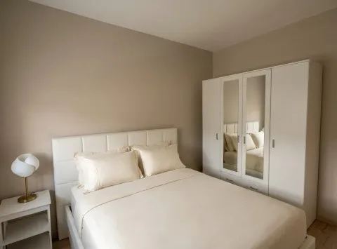 Furnished bedroom with a double bed, white wardrobe, and a nightstand. - image 6