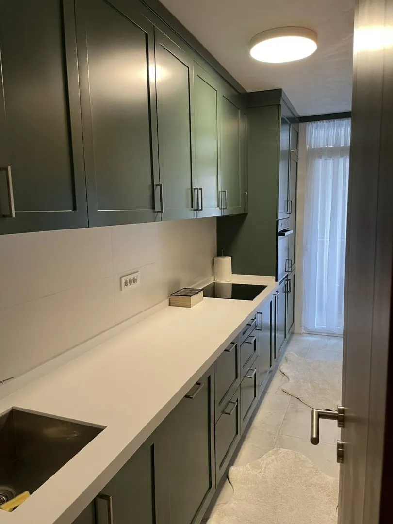 Modern kitchen with green cabinets and a white countertop.