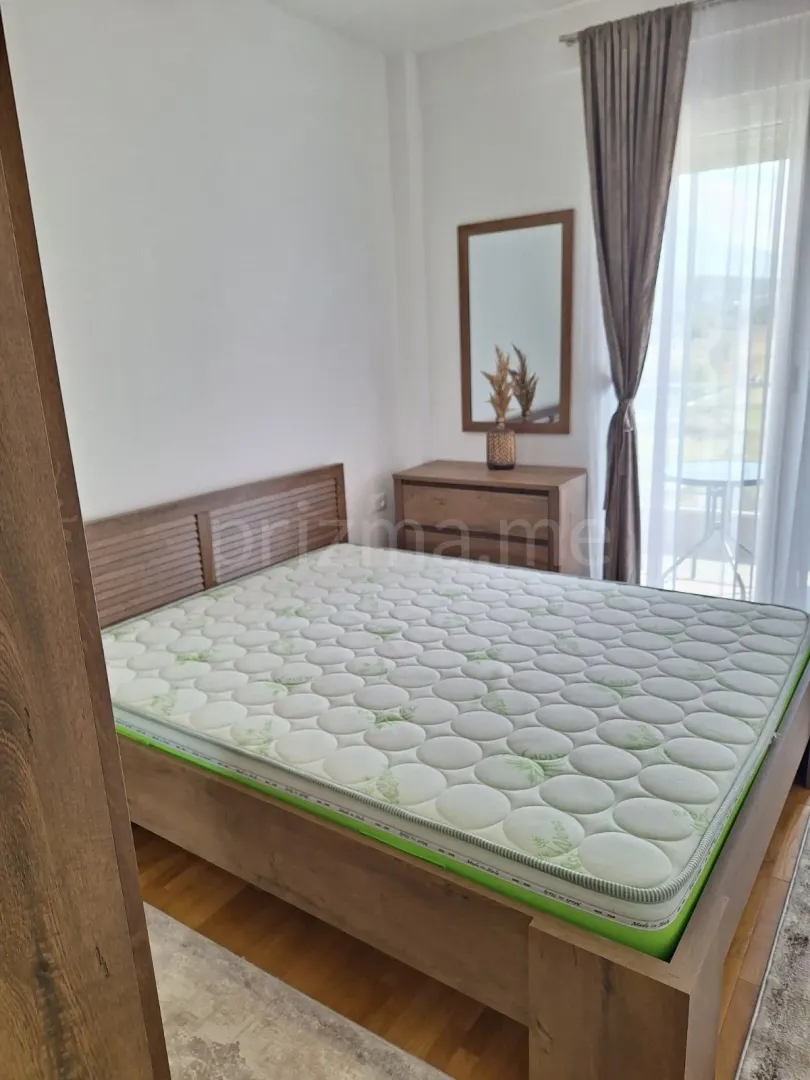Bright bedroom with a double bed, dresser, and terrace access.