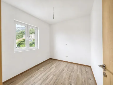 Prazna soba sa bijelim zidovima, drvenim podom i prozorom. - image 14