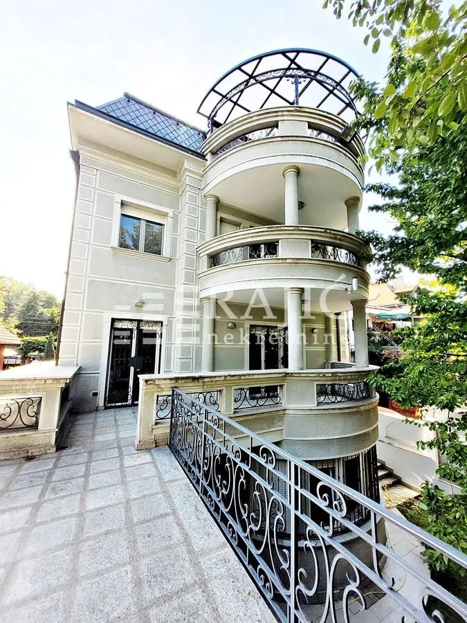 Exterior of a luxury multi-family house with terraces and wrought iron railings.