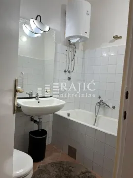 Smaller bathroom with a bathtub, washbasin, and water heater. - image 3