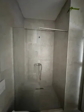 Moderno kupatilo sa tuš kabinom obloženom sivim pločicama. - image 6