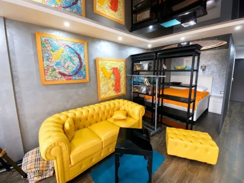 Living room with a yellow leather couch, armchair, and modern artwork on the wall. - image 3
