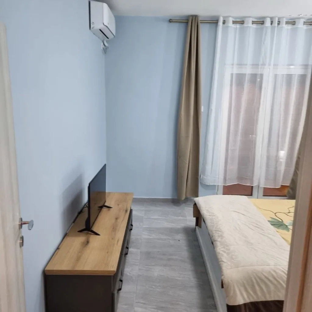 Namještena spavaća soba sa krevetom i komodom za televizor.