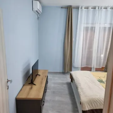 Namještena spavaća soba sa krevetom i komodom za televizor. - image 2