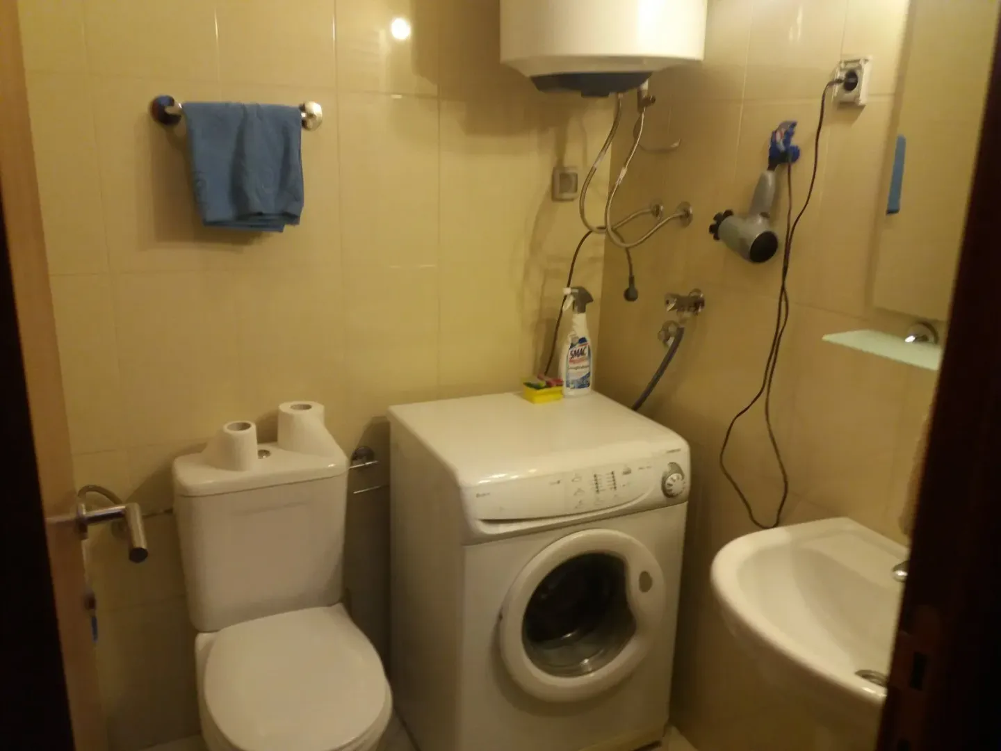 A small bathroom with a washing machine, toilet, and sink.