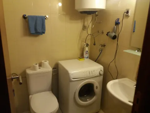 A small bathroom with a washing machine, toilet, and sink. - image 7