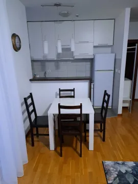Svijetla kuhinja sa trpezarijskim stolom i bijelim elementima. - image 2