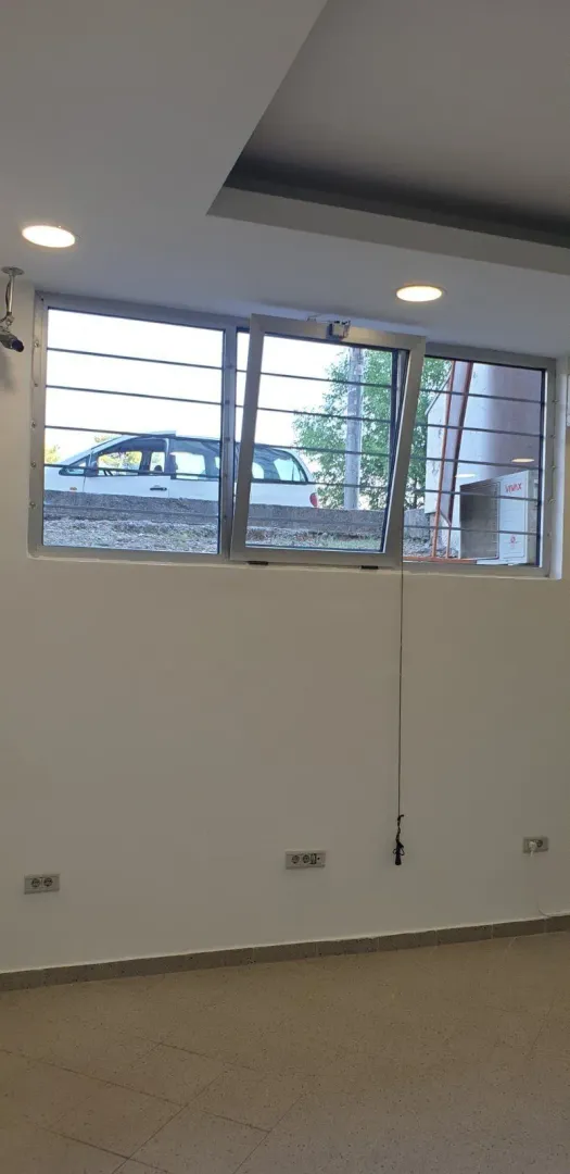 An empty room featuring a window overlooking a parking area.