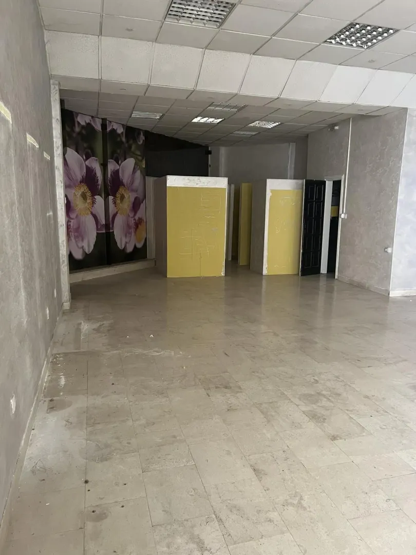 Spacious and empty commercial space with a suspended ceiling and tiled floor.