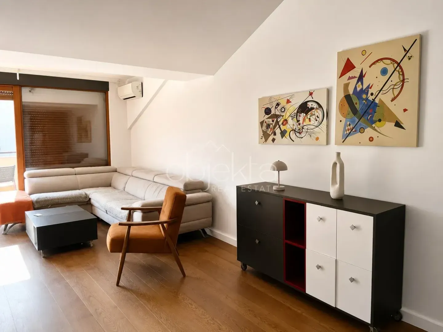 Living room with a sofa, armchair, and chest of drawers.