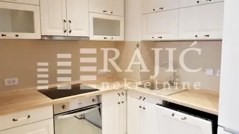 View of a bright kitchen with white cabinetry and a wooden countertop. - image 10