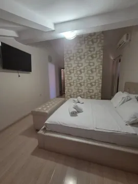 Prostrana spavaća soba sa velikim bračnim krevetom, TV-om na zidu i dekorativnim tapetama. - image 11