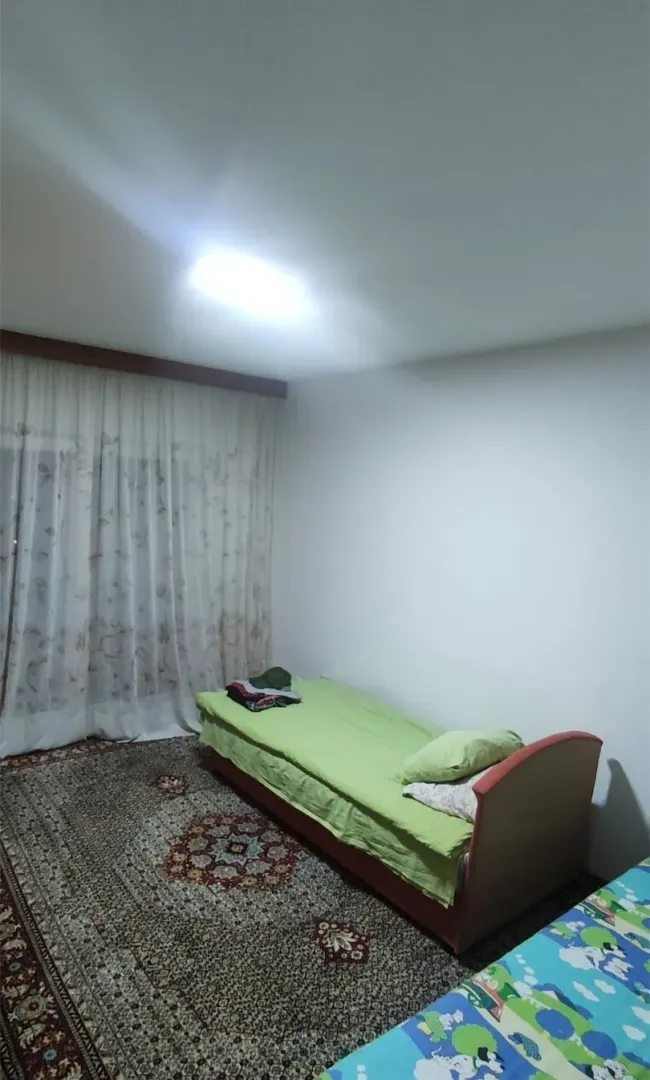 Jednostavno namještena spavaća soba sa jednim krevetom i tepihom.