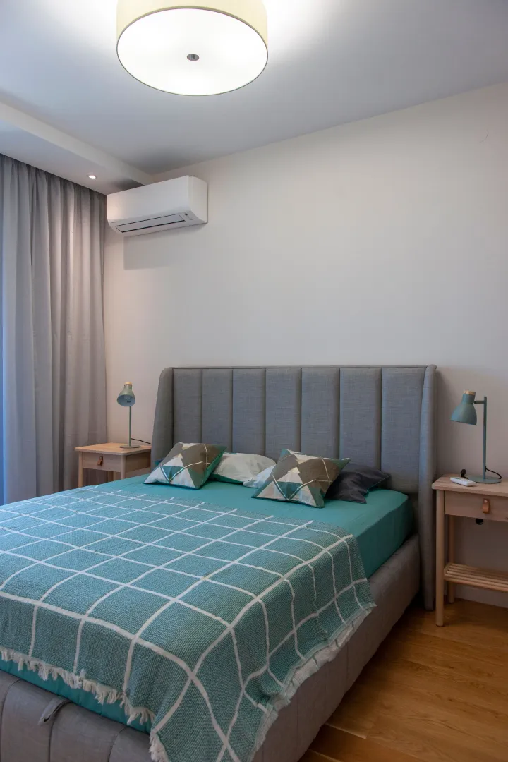 Modern bedroom with a double bed, bedside tables, and an air conditioner.