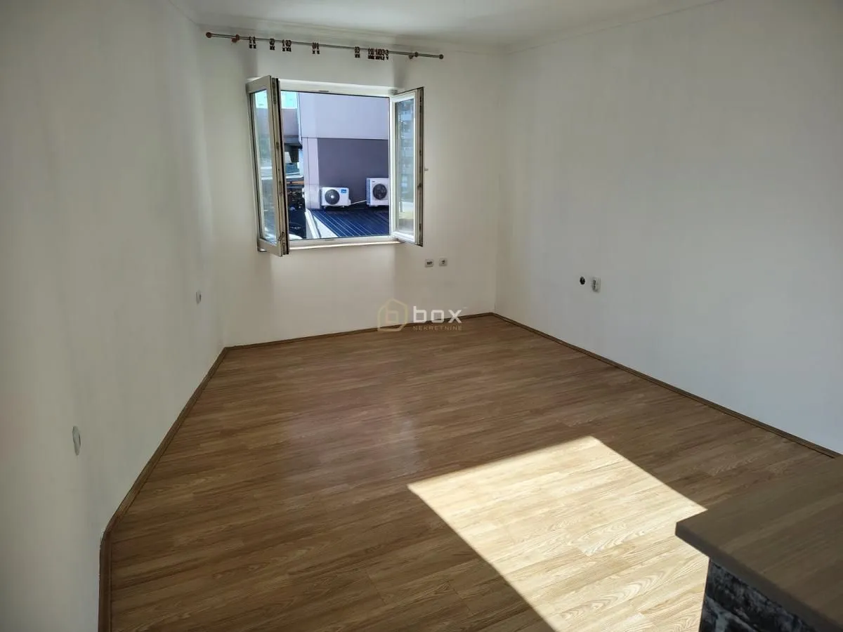 Empty room with laminate flooring and an open window.