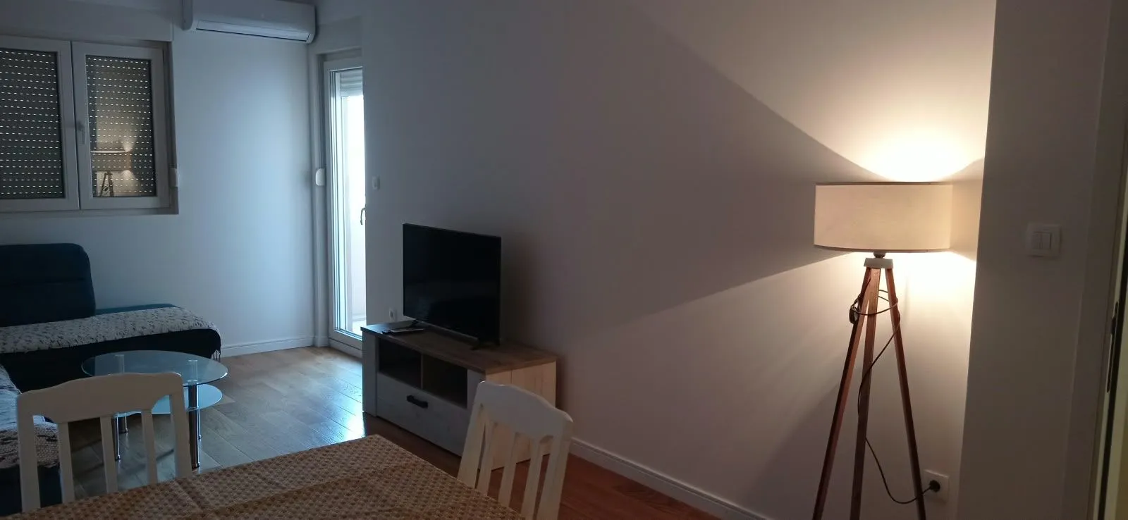 Living room with sofa, TV stand and floor lamp.