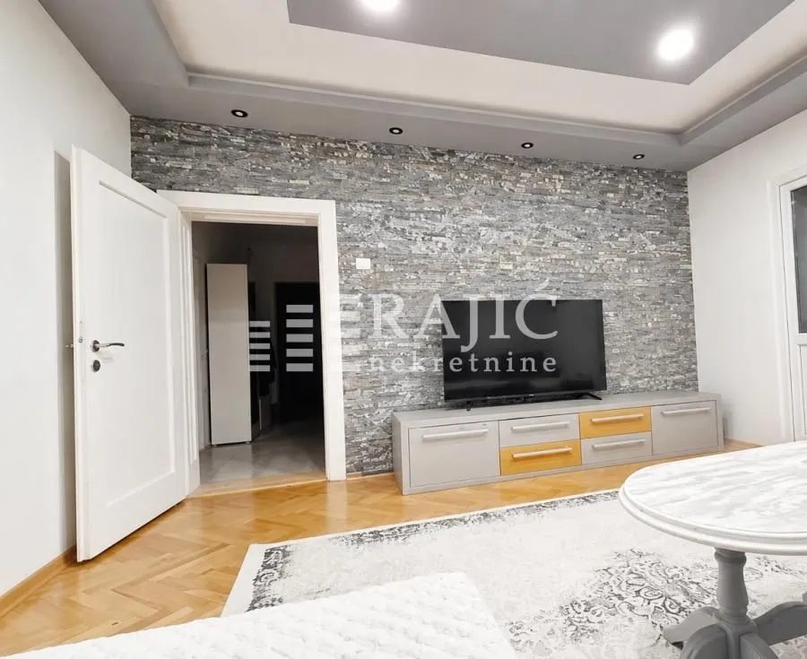 Living room with a TV unit and a decorative stone-clad wall.
