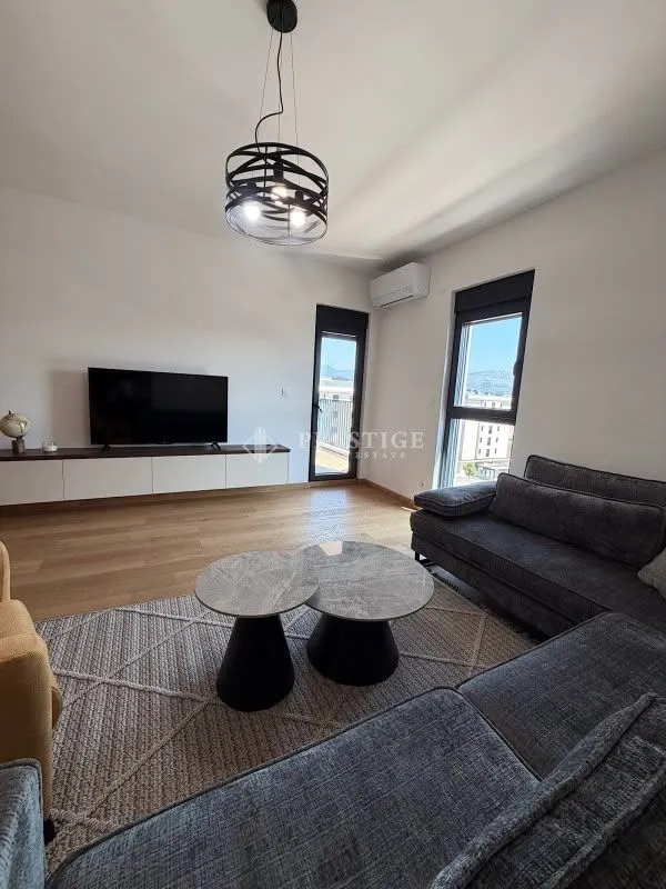 Dnevna soba opremljena garniturom, televizorom i modernim stočićima.