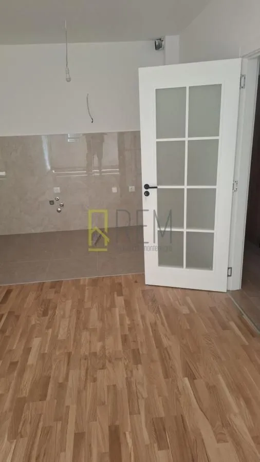 Nekororišćeni kuhinjski prostor sa pločicama i drvenim podom.