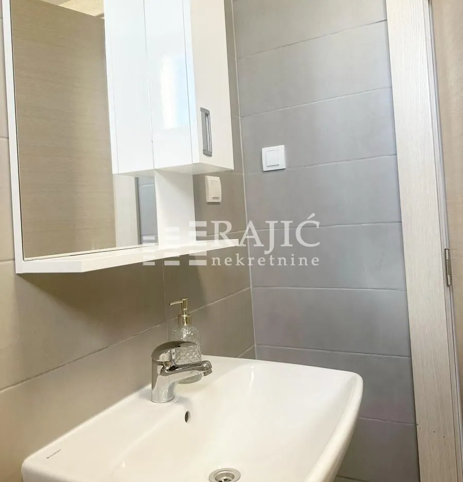 View of a portion of a modern bathroom with a sink and mirror.