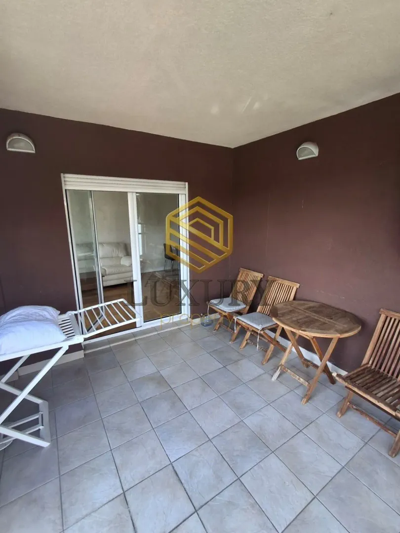 Covered terrace with a wooden table, chairs, and a drying rack.