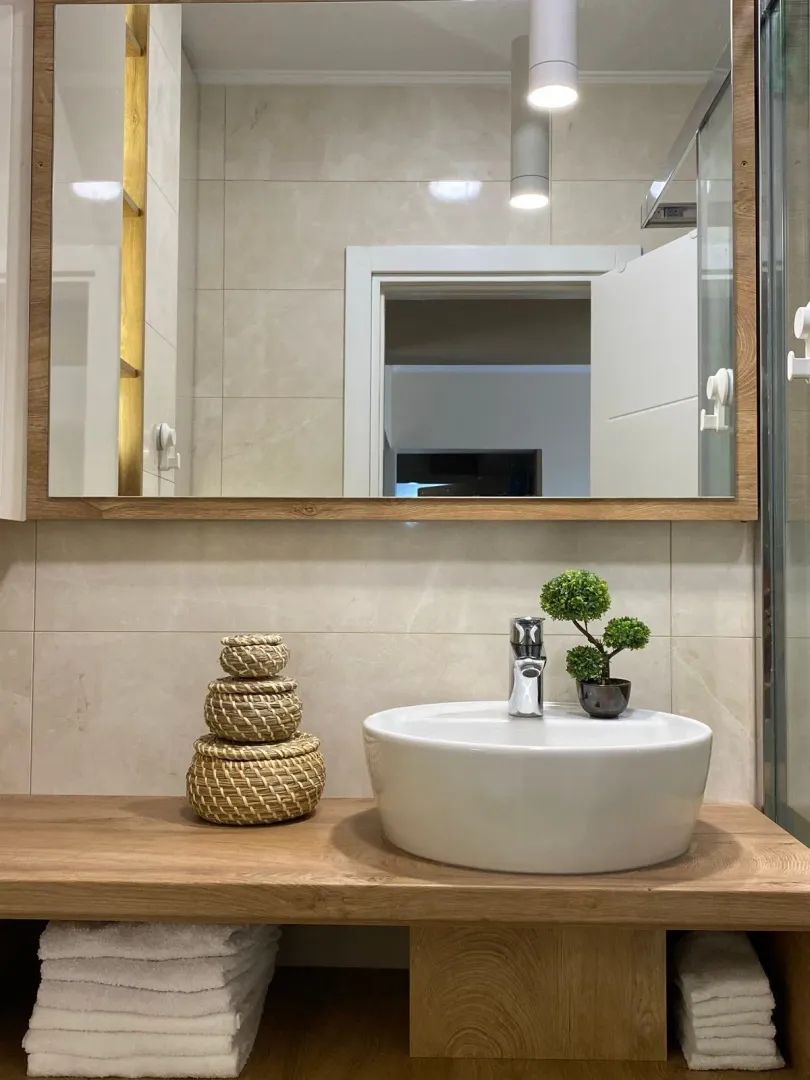 Bathroom detail featuring a basin, large mirror and decorative elements.
