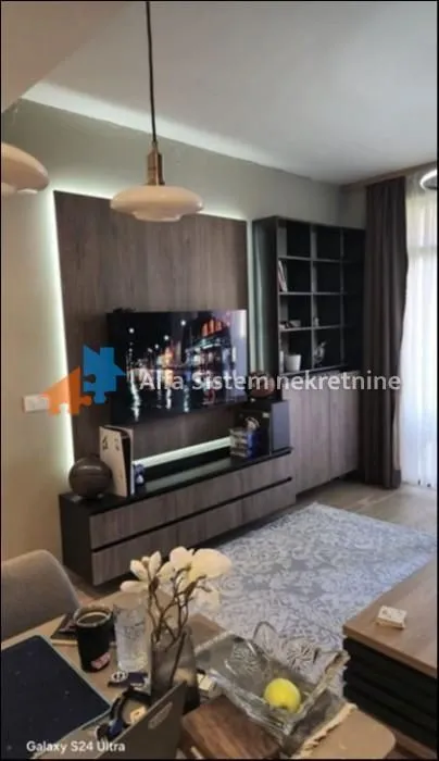 Dnevna soba opremljena modernim nameštajem i televizorom.