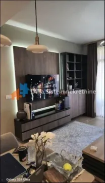 Dnevna soba opremljena modernim nameštajem i televizorom. - image 4