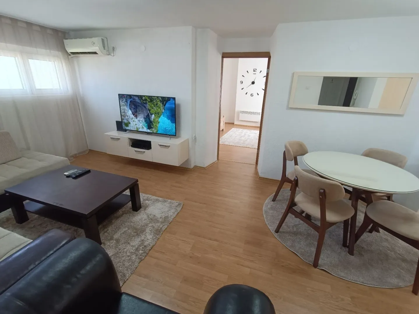 Living room with a sofa set, television, and a dining table with chairs.