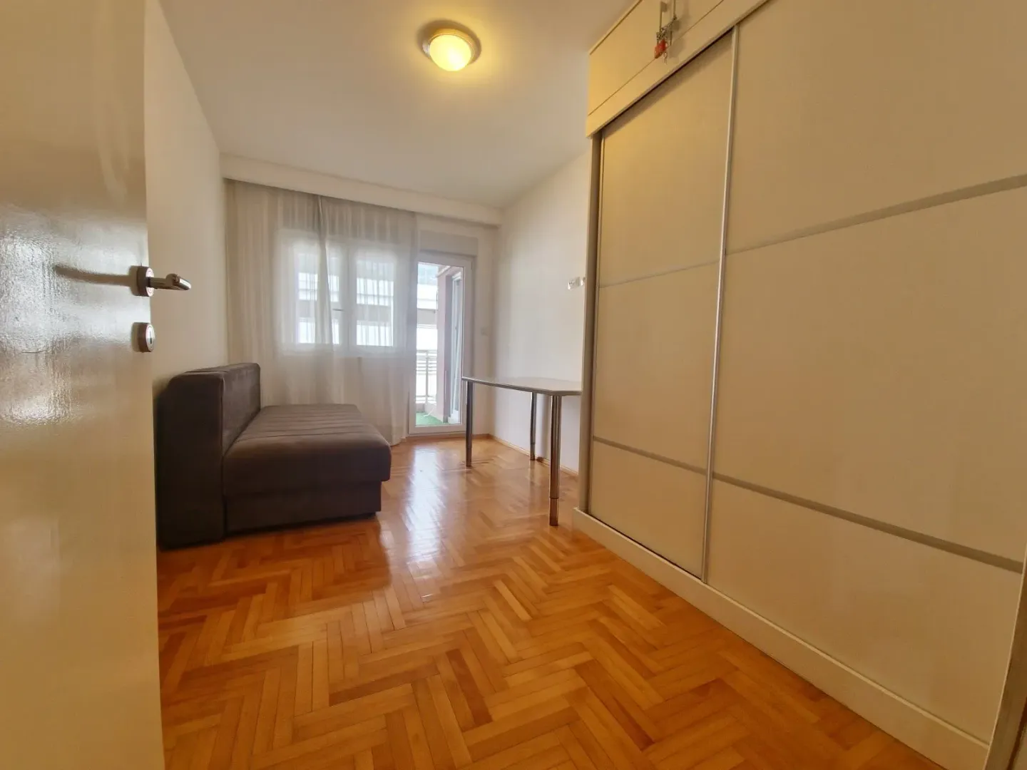 Smaller bedroom with a sofa bed, wardrobe, and access to the terrace.
