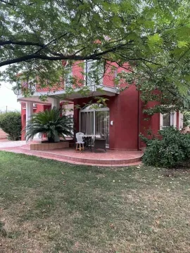 Yard with a patio in front of a red house surrounded by greenery. - image 2