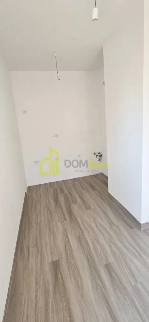 Prazna prostorija sa bijelim zidovima i laminatom na podu.