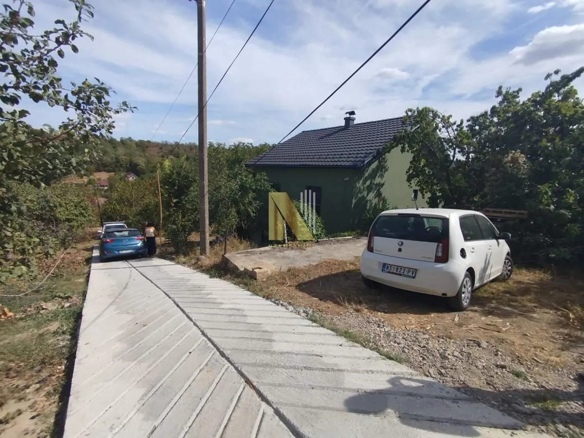 Pogled na dvorište i prilaz porodične kuće sa parkiranim automobilima.